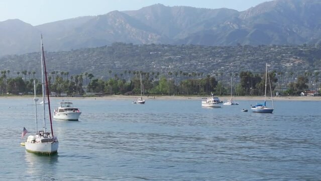 Scenic view of yachts floating in Santa Barbara Harbor, California, USA. Shot from Point Castillo on Santa Barbara city surrounded mountains and Pacific Ocean. Sailboats docked in city marina 