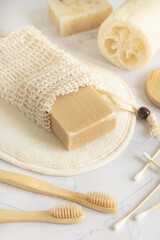 Beige handmade soap bar in soap saver bag near hygiene Items close up