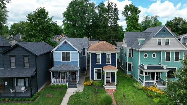 Colorful Victorian homes line a serene suburban street. Aerial push in shot.