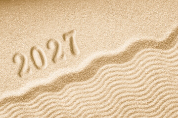 Fototapeta na wymiar Imprints of numbers 2027 happy new year on a golden sand waves