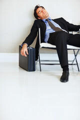 Business man, sleeping and case in lobby, chair and fatigue from travel, overworked or burnout in...