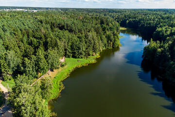 A picturesque elongated pond surrounded by forest and a walking area on the shore