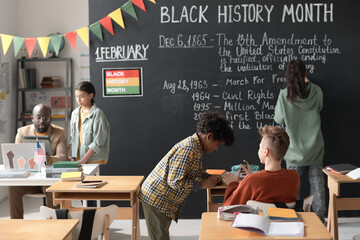 Group of school children cooperating together with teacher in the classroom, they celebrating Black History Month at school