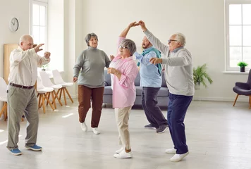 Foto op Plexiglas Retirement community. Elderly men and women actively spend time having fun and dancing at party in nursing home. Group of senior Caucasian people laughing and dancing together in living room. © Studio Romantic