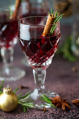 Crystal glass with red wine with cinnamon stick and rosemary. New Year's mood, celebration, Christmas composition with mulled wine.