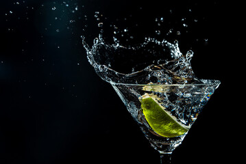 splash in a glass with lime slice on a black background