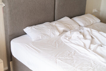 Sunlit bed sheets, tousled from sleep, evoke tranquility. Resonates with themes of restfulness in interior design trends.