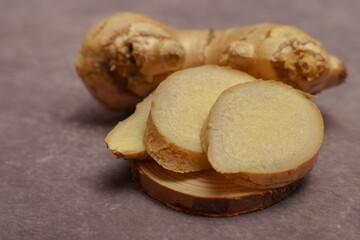 ground ginger in a wooden spoon with fresh ginger root cut in slices