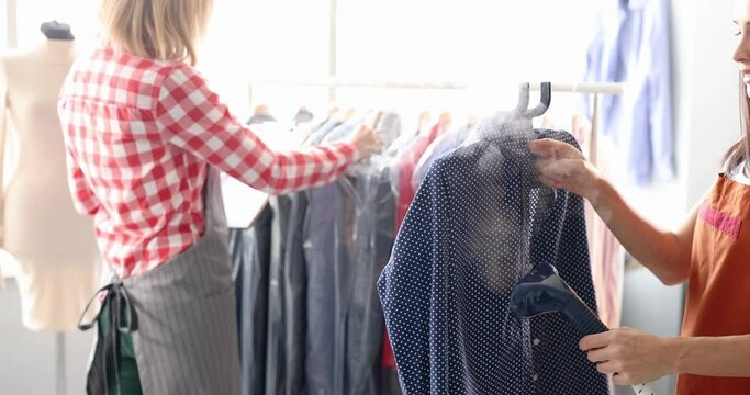 Woman seamstress ironing shirt using steamer in tailor shop 4k movie slow motion. Dry cleaning clothes concept