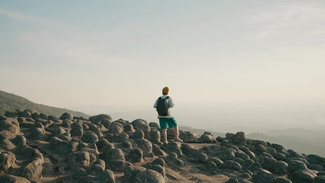 A man backpacker traveling standing and looking beautiful mountain view at Lan Hin Pum Phitsanulok National Park, Thailand. Young asian man traveling at Lan hin pum in Phu Hin Rong Kla national park