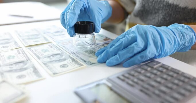 Inspector in rubber gloves looking at dollar bill using magnifying glass 4k movie slow motion. Identification of counterfeit money concept