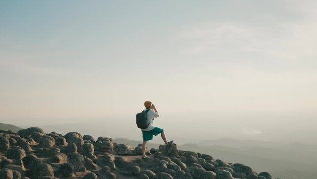 Happy young asian man backpacker traveling standing and looking beautiful mountain view at Lan Hin Pum Phitsanulok National Park, Thailand. Travel and backpack concept