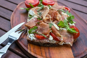 Tomaten-Schinkenbrot, Holzbrett, Besteck
