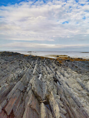 The rocky coast of the Barents Sea. Beautiful view of the rocks and the coast of the Rybachy and Sredny peninsulas, Murmansk region, Russia. The landscape is the harsh beauty of the north.