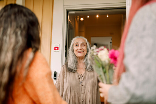 Happy senior woman welcoming family at entrance of house