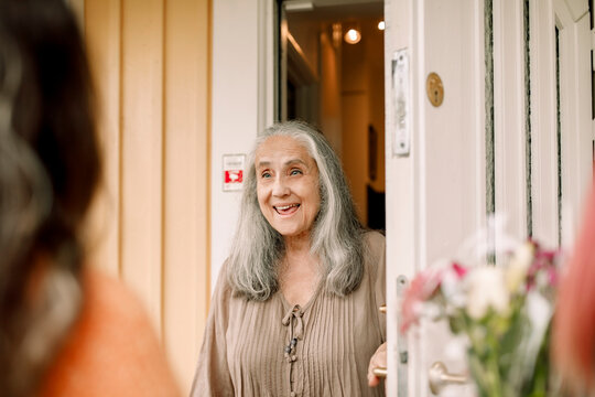Excited senior woman standing at doorway of house