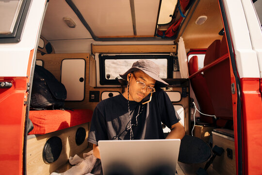 Young man multi-tasking while sitting in van during vacation