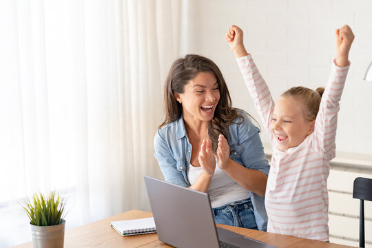 Mother and daughter learning together at home, sitting at the desk in front of a computer. Back to school
