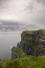 Vertical photo with copy space of cliffs in Ireland with a cloudy gray sky and green meadow.