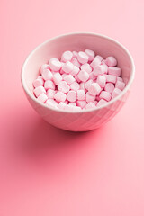 Fototapeta na wymiar Mini sweet marshmallows candy in bowl on pink background.
