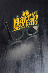Happy new year background. Black funny paper glasses on black table.