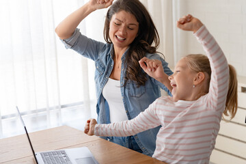 A joyful mother and her adorable little girl are having a great time, dancing together in front of...