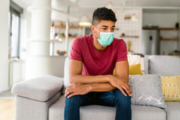 Portrait of a black man wearing surgical mask at home. Covid-19, coronavirus and quarantine concept.