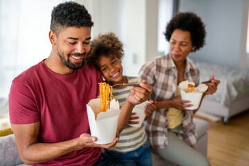Fototapeta na wymiar Happy african family eating at living room and enjoying time together. Home delivary takeaway food