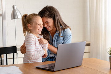 A cheerful mother and daughter engage in a video call over a laptop computer, sharing smiles and moments of connection