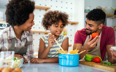 Happy african american parents and child having fun preparing healthy food in kitchen