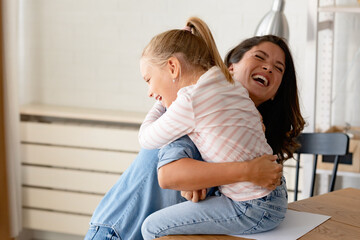 A child loves her mother. Cheerful smiling mother and daughter cuddling, hugging, and having fun at home. Mothers day