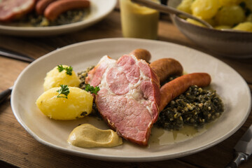 2 Portionen Oldenburger Grünkohl mit geräucherter Kohlwurst, Pinkel, Kassler Nacken, Kartoffeln, Senf, Petersilie auf Teller und Holz Hintergrund