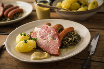 2 Portionen Oldenburger Grünkohl mit geräucherter Kohlwurst, Pinkel, Kassler Nacken, Kartoffeln, Senf, Petersilie auf Teller und Holz Hintergrund