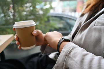 Fototapeta na wymiar Businesswoman looking on her wrist watch while sitting near office window