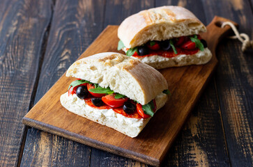 Ciabatta with cheese, tomatoes, sausage, olives and arugula. Sandwich. Italian food.