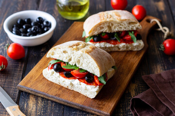 Ciabatta with cheese, tomatoes, sausage, olives and arugula. Sandwich. Italian food.