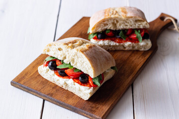 Ciabatta with cheese, tomatoes, sausage, olives and arugula. Sandwich. Italian food.