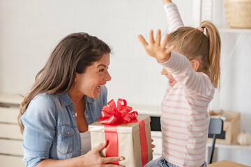 A sweet and adorable little girl pleasantly surprises her mother with a thoughtful gift on Mother's...