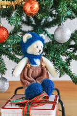 Self knitted cute teddy bear under the beautifully decorated Christmas tree