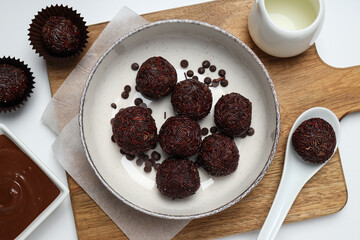 Brigadeiro on plate and spoon on kitchen board on white background, top view