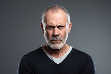 A serious and sad senior Caucasian man with a harsh expression, conveying a dramatic and thoughtful mood in a studio portrait.