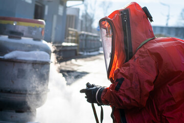 Firefighters in protective chemical HAZMAT suits stop the leak of the dangerous substance ethylene...