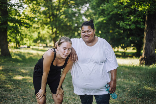 Smiling oversize woman with tired female friend after exercising at park
