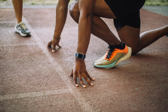 Low section of man kneeling at starting line on running track