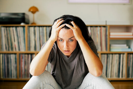 Portrait of stressed woman with head in hands sitting at home