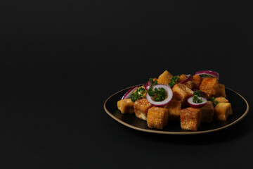 Fried tofu in a bowl on a dark background