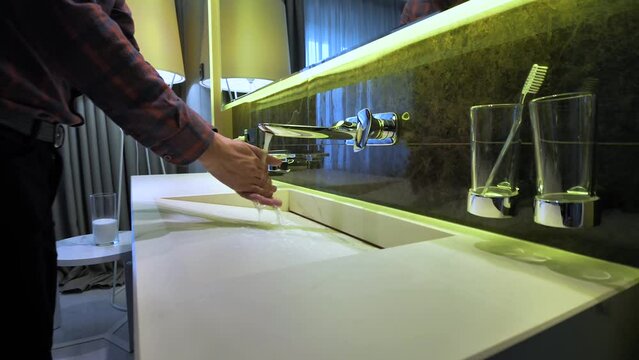 modern bathroom design light turns on, young man enters and washes his hands close-up, then turns off the water and leaves, light goes out
Showcasing personal hygiene and responsible resource usage