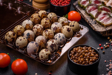 Raw quail eggs in a plastic box on a dark concrete background