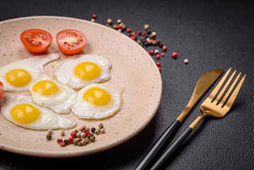 Delicious nutritious breakfast of fried quail eggs, bacon, legumes and cherry tomatoes