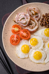 Delicious nutritious breakfast of fried quail eggs, bacon, legumes and cherry tomatoes